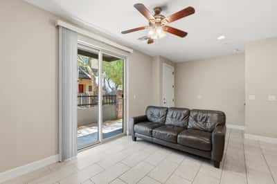 Comfortable living area with large sliding glass doors opening to the private patio. Natural light, tile flooring, and an open design enhance the home's inviting atmosphere.