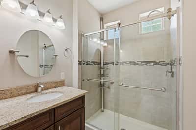 Elegant walk-in shower with glass enclosure, tile surround, and contemporary finishes. Paired with a granite vanity, this bathroom offers both style and convenience.