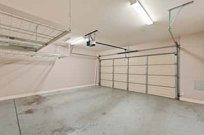 Large two-car garage featuring overhead storage systems, ample parking space, and room for tools or recreational equipment. Designed for both convenience and organization.