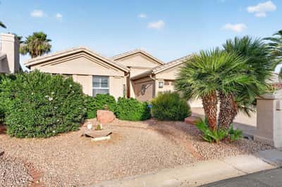 Low-maintenance desert landscaping, mature greenery, and decorative accents create an inviting front yard. This attractive outdoor setting enhances the home's curb appeal and complements the Arizona lifestyle.