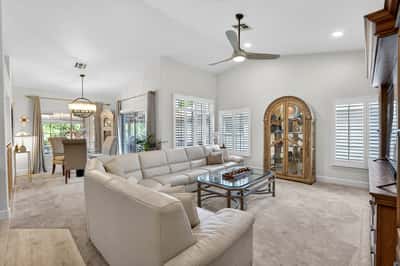 The open layout combines living, dining, and kitchen spaces into one cohesive design. Plantation shutters, vaulted ceilings, and abundant natural light create an airy and inviting environment.