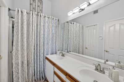 Featuring dual sinks, expansive mirrors, and generous counter space, this bathroom offers both style and functionality. Updated fixtures and bright finishes create a welcoming atmosphere.