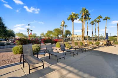 Enjoy resort-style lounging with shaded seating, palm-lined landscaping, and easy access to community recreational amenities. A perfect setting for outdoor enjoyment.