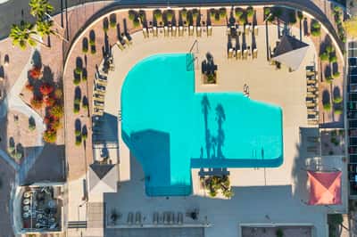 A bird's-eye view of the community pool reveals spacious deck areas, shaded seating, and attractive landscaping. Residents enjoy resort-inspired amenities designed for relaxation and recreation.