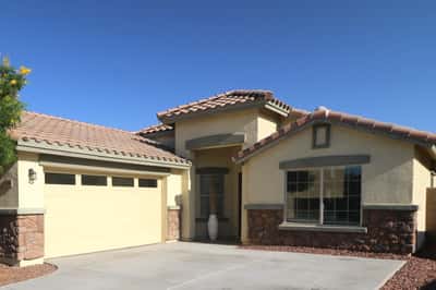 The charming covered entry and stone-accented exterior create a warm welcome while the spacious driveway and attached garage add everyday convenience to this beautifully maintained Buckeye property.