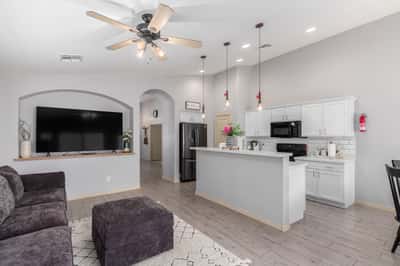 The stylish kitchen showcases white quartz countertops, white cabinetry, recessed lighting, a spacious breakfast bar, and open sightlines to the family room, making meal preparation and entertaining easy.