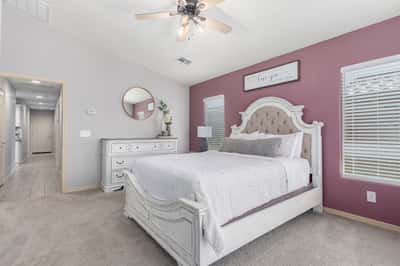 Unwind in the spacious primary suite offering plush carpet, large windows, neutral colors, and generous room for a sitting area or additional furnishings, creating a relaxing retreat.