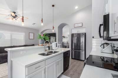 White quartz countertops, crisp white cabinetry, a spacious breakfast bar, and an open floor plan make this stylish kitchen the heart of the home. Perfect for entertaining and everyday living.