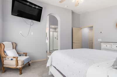 The spacious primary bedroom offers plush carpeting, a ceiling fan, neutral finishes, and convenient access to the ensuite bathroom. A peaceful retreat designed for comfort and relaxation.