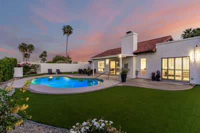The beautifully illuminated backyard offers a resort-inspired atmosphere with a sparkling pool, covered patio, and lush landscaping, creating an exceptional setting for outdoor entertaining and relaxation.