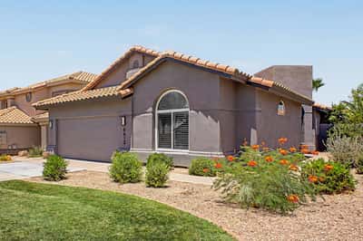 Attractive front exterior featuring mature landscaping, a spacious driveway, and timeless architecture in the desirable Red Mountain Ranch community. This well-maintained home offers exceptional curb appeal from the moment you arrive.