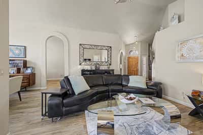 Bright family room featuring a fireplace, plantation shutters, vaulted ceilings, and an open layout that enhances everyday living. A comfortable gathering place at the heart of the home.