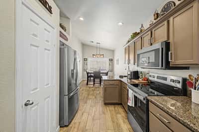 Bright kitchen overlooking the adjacent dining space, featuring granite countertops, stainless steel appliances, abundant cabinet storage, and durable tile flooring throughout.