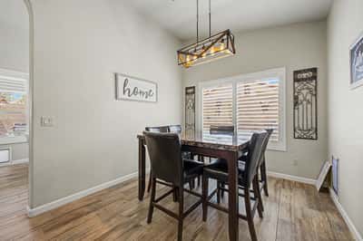Comfortable dining area featuring modern lighting, plantation shutters, tile flooring, and plenty of natural light. An inviting space perfect for casual meals and everyday gatherings.