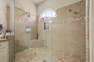 Elegant walk-in shower with a frameless glass enclosure, custom tile surround, decorative accents, and built-in shelving. A luxurious feature that adds comfort and sophistication to the primary bathroom.