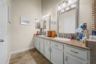 Elegant primary bathroom with dual sinks, expansive vanity, framed mirrors, generous storage, and bright lighting. A thoughtfully designed space that blends comfort and functionality.