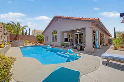Beautiful backyard showcasing a private swimming pool, expansive covered patio, mature desert landscaping, and multiple outdoor living spaces. A perfect combination of comfort, style, and low-maintenance living in Mesa.