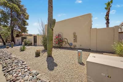 Attractive desert landscaping showcases mature cactus, decorative stone, and native plants designed for beauty and easy maintenance. The enclosed yard enhances privacy while complementing the home's architecture.