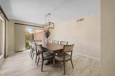 This inviting dining room offers generous seating, stylish lighting, updated flooring, and direct access to the patio, making it ideal for everyday meals and entertaining family and friends.