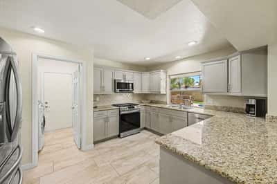 The remodeled kitchen showcases granite countertops, stainless steel appliances, recessed lighting, and generous cabinet storage. The open layout offers both style and functionality for modern Scottsdale living.