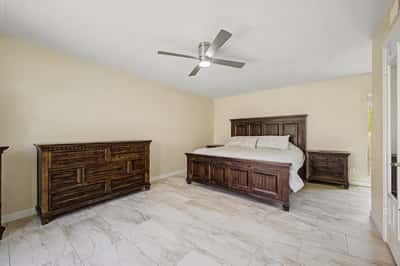 This generous primary bedroom offers plenty of room for large furnishings, updated flooring, neutral finishes, and a ceiling fan. A comfortable owner's retreat designed for everyday luxury and relaxation.