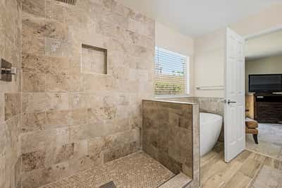 The spacious walk-in shower showcases floor-to-ceiling tile, built-in storage niche, and modern fixtures. A soaking tub and updated finishes complete this luxurious primary bathroom.