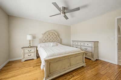 This welcoming bedroom features wood-look flooring, a ceiling fan, generous natural light, and neutral finishes. A versatile space ready to accommodate guests or family.