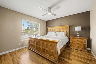 Spacious guest bedroom featuring attractive wood-look flooring, ceiling fan, neutral finishes, and a large window for natural light. A welcoming space offering comfort and flexibility in this Scottsdale property.