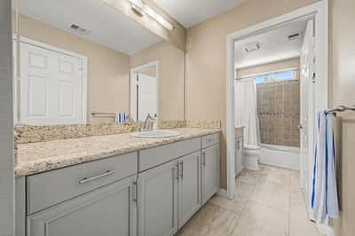 Updated guest bathroom showcasing granite countertops, modern gray cabinetry, upgraded fixtures, and tile flooring. A stylish bathroom designed for everyday comfort and convenience.