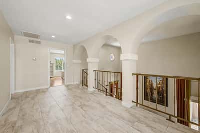 Beautiful upper-level loft accented by decorative arches, open railings, recessed lighting, and upgraded flooring. An inviting flexible space with impressive architectural character.