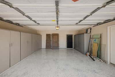 Finished garage with epoxy-coated flooring, abundant built-in storage cabinets, and generous room for vehicles, tools, and extra storage. A practical feature that complements this Scottsdale home.