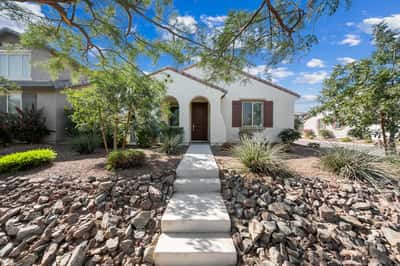 Attractive front elevation featuring mature desert landscaping, charming architecture, and a welcoming covered entrance. This move-in ready Goodyear property offers exceptional curb appeal from the moment you arrive.