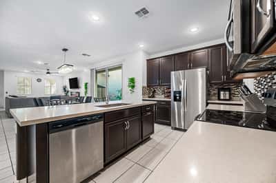 Open-concept kitchen featuring quartz countertops, stainless steel appliances, a large center island, and abundant cabinetry. Pe