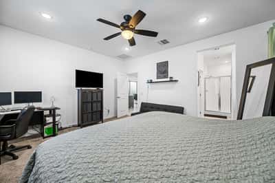 Bright owner's suite featuring plush carpet, ceiling fan, generous layout, and flexible space for additional seating or a workspace. A welcoming retreat within this Goodyear home.