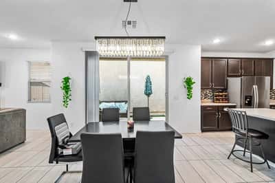 Dining space with contemporary lighting and sliding glass doors leading to the backyard. Ideal for hosting family dinners or enjoying indoor-outdoor living throughout the year.