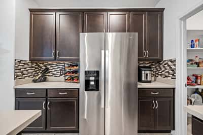 Modern kitchen offering quartz countertops, stainless steel appliances, rich cabinetry, and an oversized walk-in pantry. A beautiful blend of style, storage, and everyday functionality.