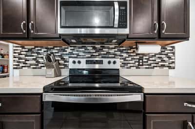 Detailed view of the upgraded kitchen featuring stainless steel appliances, quartz counters, decorative backsplash, and ample cabinetry. Designed for both beauty and performance in this move-in ready Goodyear home.
