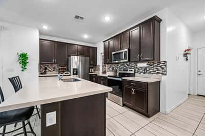 Another view of the beautifully designed kitchen featuring quartz countertops, stainless steel appliances, decorative backsplash, and abundant cabinet storage for everyday convenience.