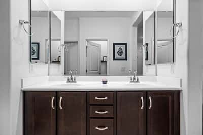 Primary bathroom featuring a spacious double vanity, oversized mirrors, abundant cabinet storage, and modern fixtures. A bright and functional space designed for everyday comfort.