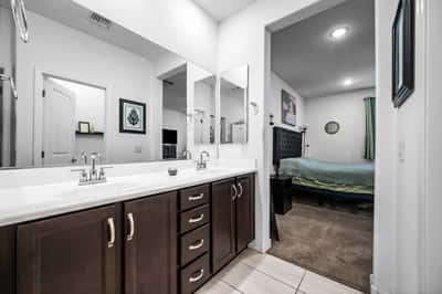 Another view of the primary bathroom highlighting the dual vanity, modern cabinetry, and seamless connection to the owner's suite. Designed for convenience and relaxation.