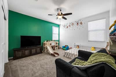 Spacious bedroom featuring plush carpeting, ceiling fan, and natural lighting. Perfect as a guest room, children's room, hobby space, or home office in this move-in ready Goodyear home.