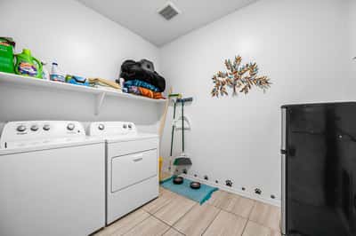 Functional laundry room with built-in shelving, washer and dryer, and additional storage space. Designed to keep household tasks organized and efficient while maximizing utility.