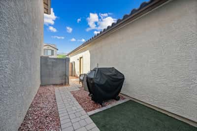 Functional outdoor side yard offering artificial grass, paver pathways, and easy-care landscaping. A practical extension of the home's outdoor living areas in Goodyear.