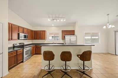 Spacious open kitchen with breakfast bar seating, stainless steel appliances, generous cabinetry, and easy access to the adjoining living and dining spaces.