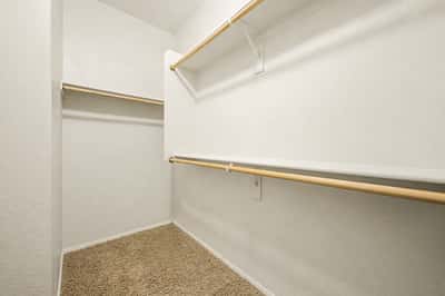 Large walk-in closet featuring multiple hanging rods and generous storage space, helping keep the primary suite organized and clutter-free.