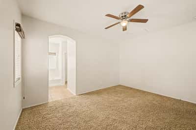 Peaceful primary bedroom offering soft carpeting, ceiling fan, and convenient access to the ensuite bath, providing comfort and privacy.