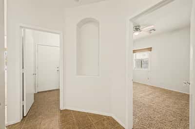 Elegant hallway leading to the primary bathroom, showcasing tile flooring, arched entryways, and decorative architectural details.