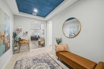 Welcoming foyer featuring a custom wood front door, tray ceiling, upgraded tile flooring, and stylish finishes that create an elegant entrance into this beautifully designed home.