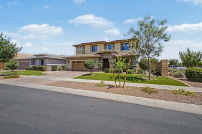Beautifully landscaped front yard with mature trees, manicured greenery, stone accents, and timeless architecture that enhances the charm and appeal of this Mesa home.