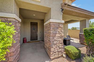 Covered front entry features stone accents, a custom wood front door, and a relaxing porch that welcomes guests while adding timeless character to this beautifully maintained home.